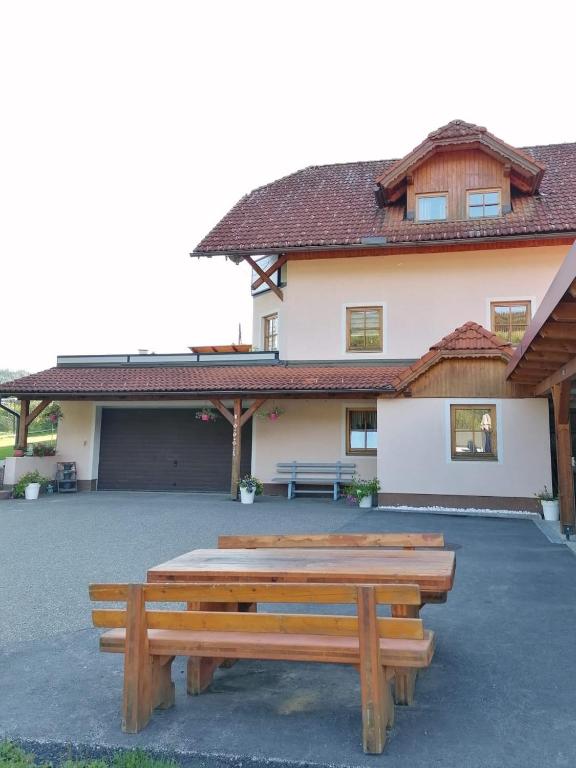 a patio with two wooden benches in front of a house at Ferienwohnung Familie Pichler in Neumarkt in Steiermark