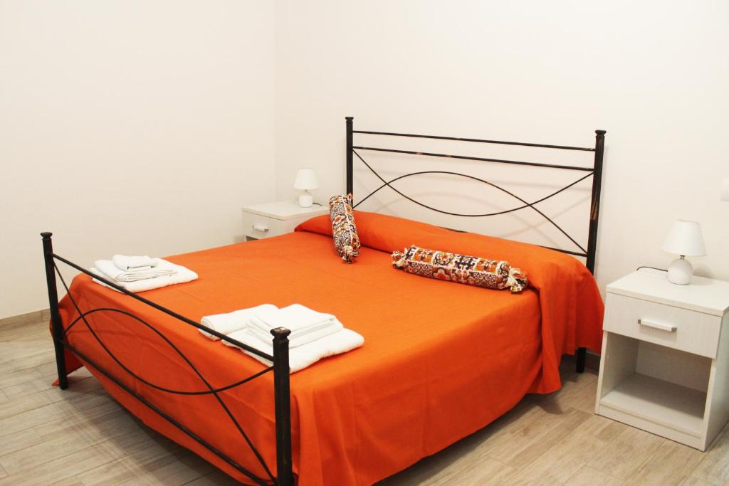 ein großes orangenes Bett mit zwei Handtüchern darauf in der Unterkunft B&B Ciccannina in Rosolini