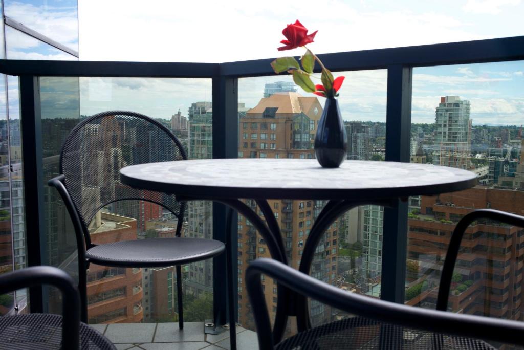 a table with a vase with a flower on a balcony at Your Alternative to a Five Star Hotel - Premium Location in Vancouver