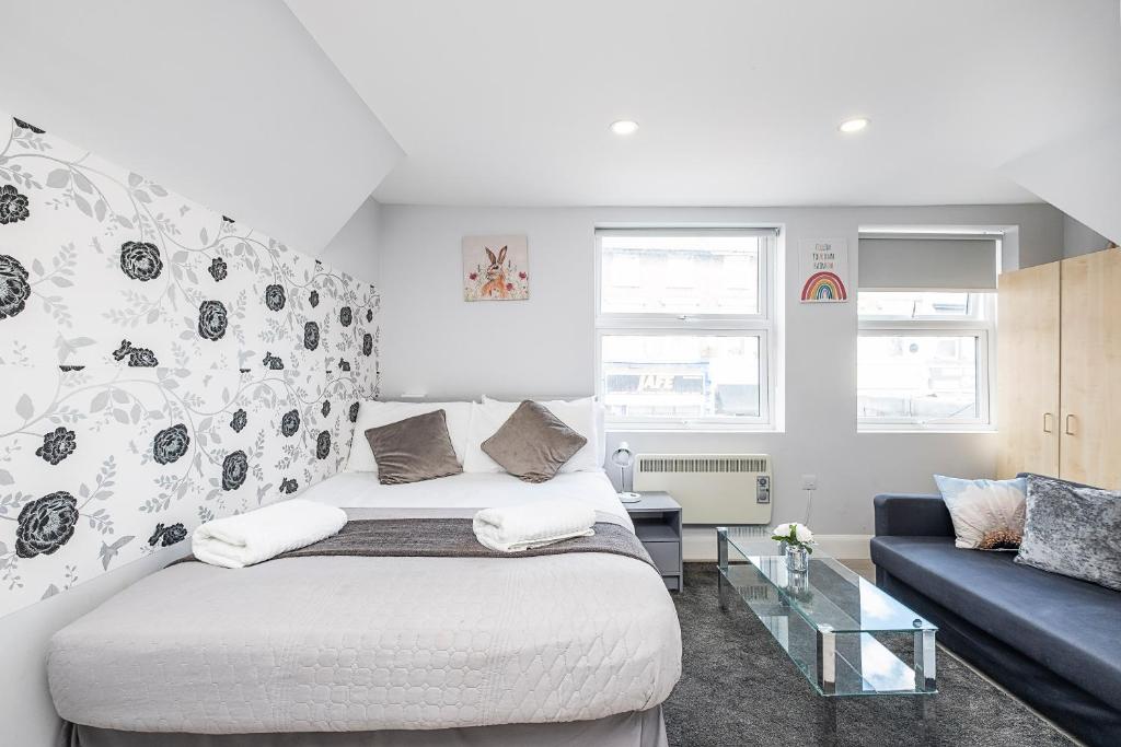um quarto com uma cama e um sofá em Securematics Queens Studio Apartments em Londres