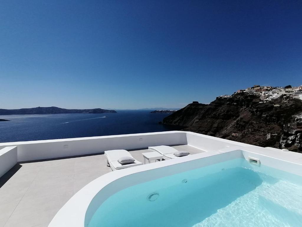 uma piscina com duas cadeiras e vista para o oceano em Archontiko Suites Santorini em Fira