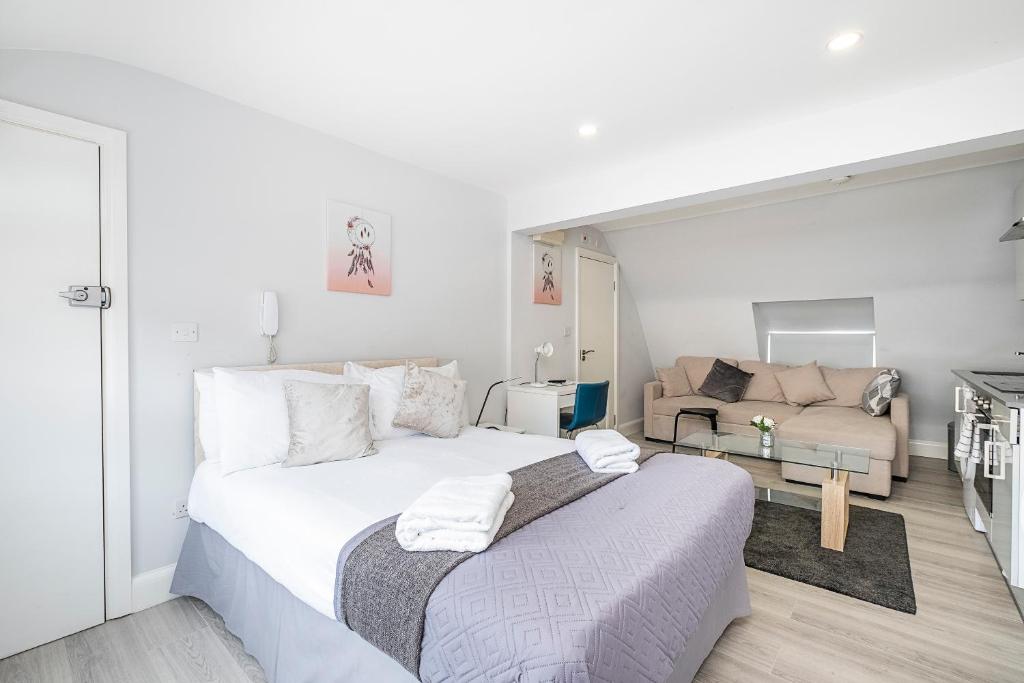a white bedroom with a large bed and a couch at Securematics Superior Studio Apartments in London