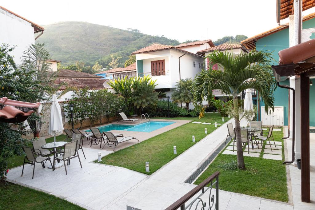 Vistas a una casa con piscina, mesas y sillas en Vila Hibisco Pousada e Apart en Vassouras