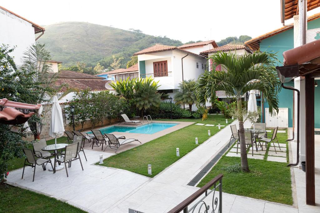 a view of a house with a pool and tables and chairs at Vila Hibisco Pousada e Apart in Vassouras