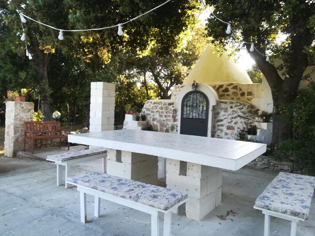 una mesa de picnic y dos bancos frente a un edificio en Trullo Alessandro e Villa Raffaela, en San Vito dei Normanni