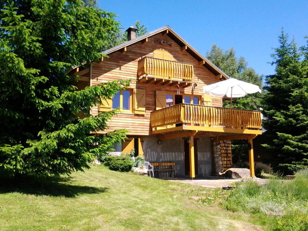 a wooden house with a balcony and an umbrella at Chalet de 4 chambres avec jardin amenage a Ax les Thermes a 1 km des pistes in Ax-les-Thermes