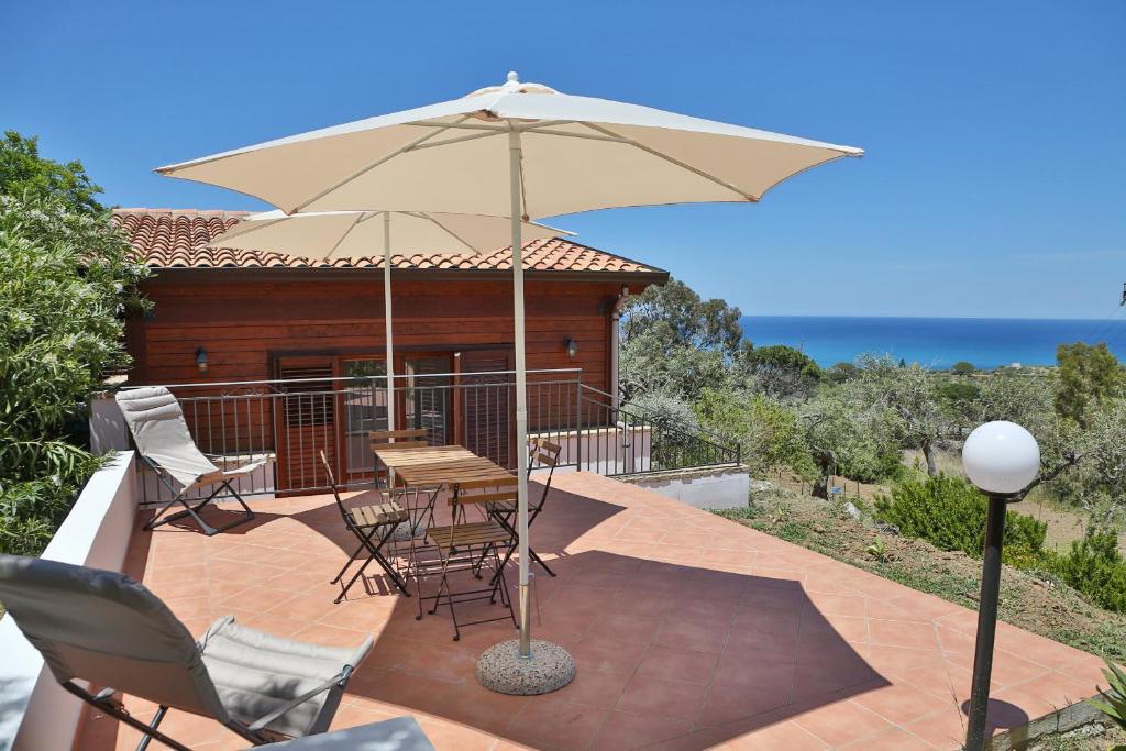 une terrasse avec une table, des chaises et un parasol dans l'établissement Agli Ulivi Cefalù - by Vacation Service, à Cefalù