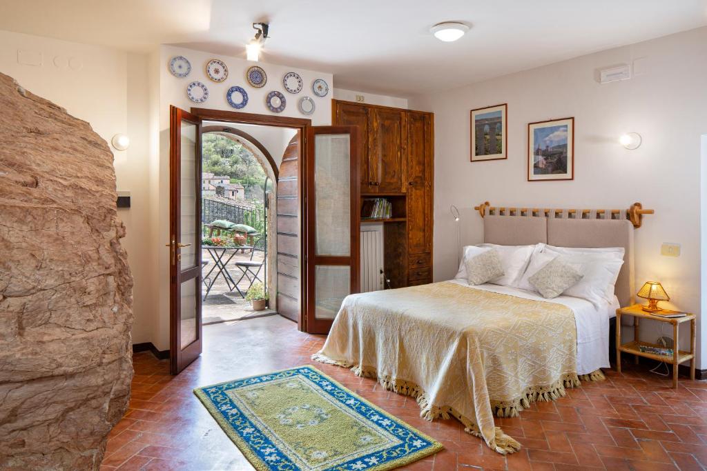 1 dormitorio con 1 cama y puerta abierta a un balcón en Residence Menotre, en Rasiglia