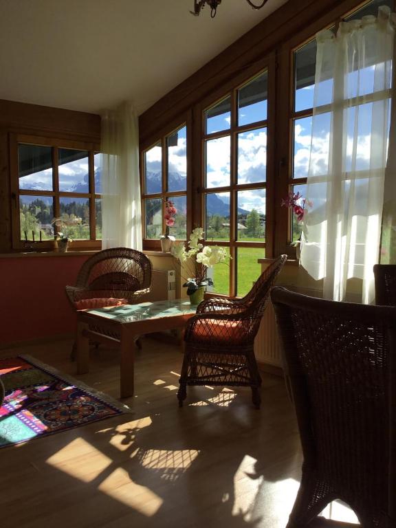 salon ze stołem, krzesłami i oknami w obiekcie Ferienwohnung Orchidee w mieście Kössen