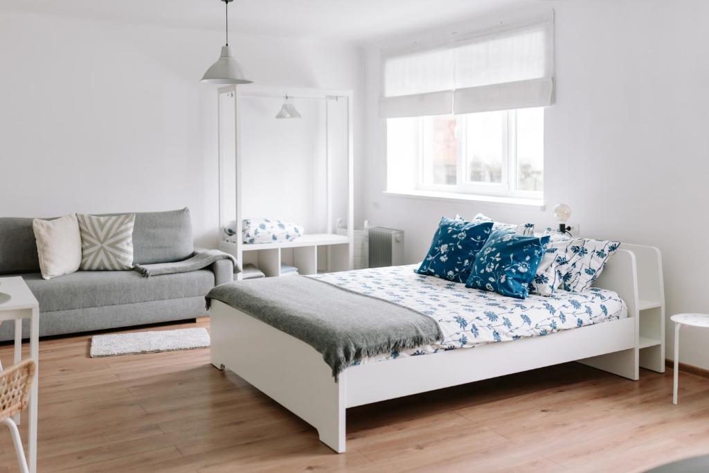 ein weißes Schlafzimmer mit einem Bett mit blauen Kissen in der Unterkunft Lake Aluksne studio apartment in Alūksne