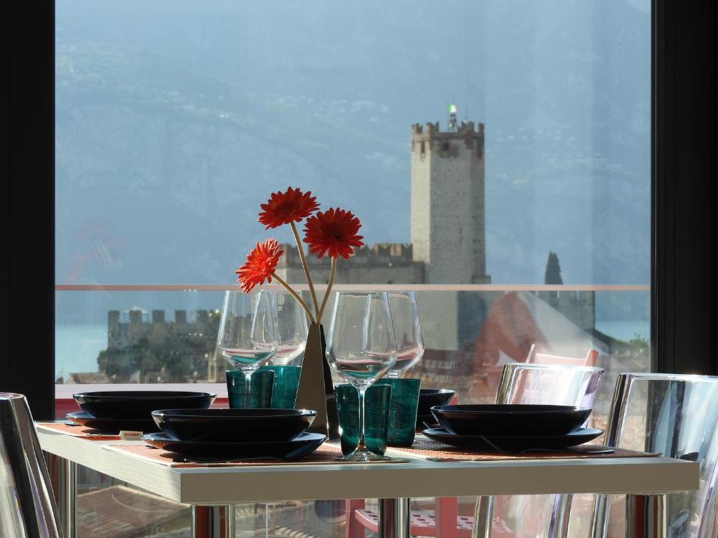 una mesa con vasos y un jarrón con una flor. en Blue Sky Garda - Sunset, en Malcesine