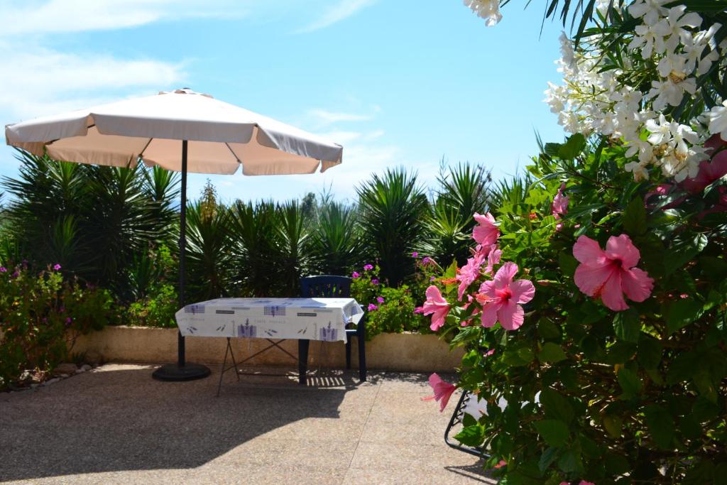 a table with an umbrella and some pink flowers at Casa Alexandra in Casas Devesa