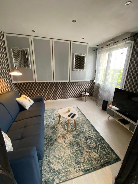 un salon avec un canapé bleu et une table dans l'établissement Verdun, à Mantes-la-Jolie