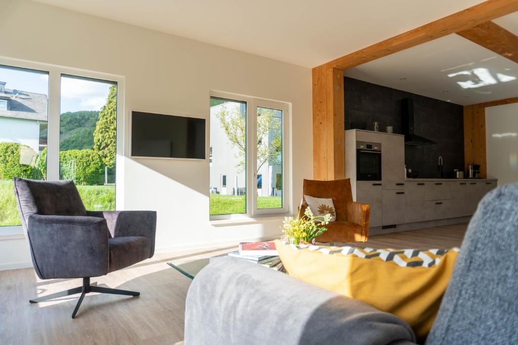 a living room with a couch and chairs and windows at Velo & Wohnen -NEU- Elektroräder inklusive - Sauna in Traben-Trarbach