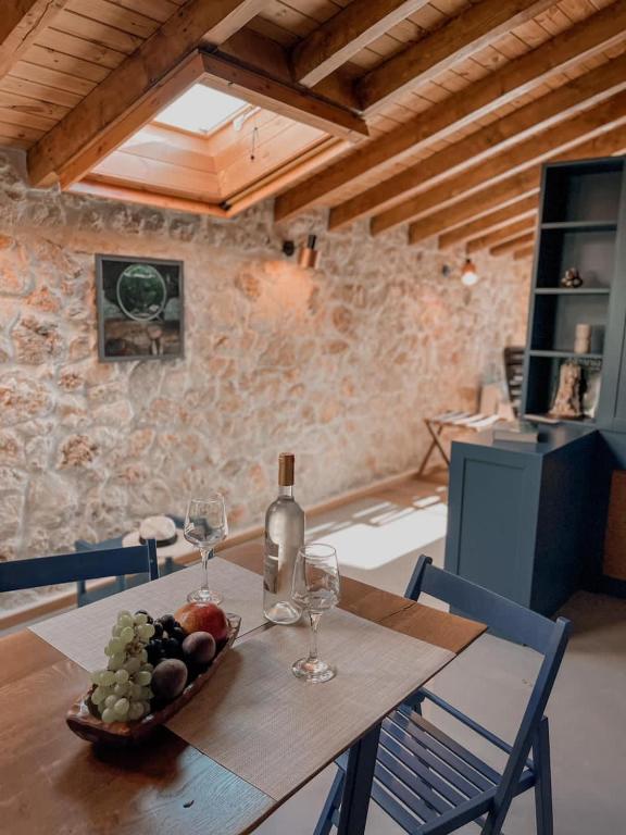 a table with a bowl of fruit and a bottle of wine at Roots Dhermi in Dhërmi