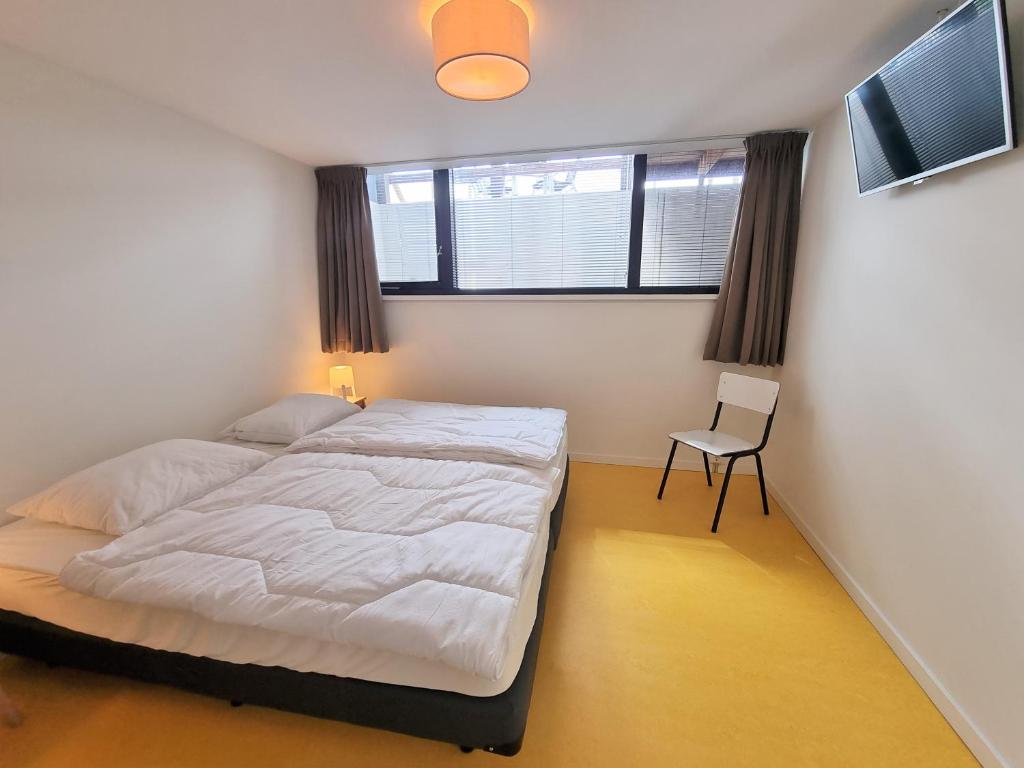 A bed or beds in a room at NIEUW DOMBURG centrum - Luxe vakantiewoning 500 meter van strand met tuin en parkeerplaats & WIFI - Roosjesweg 2A