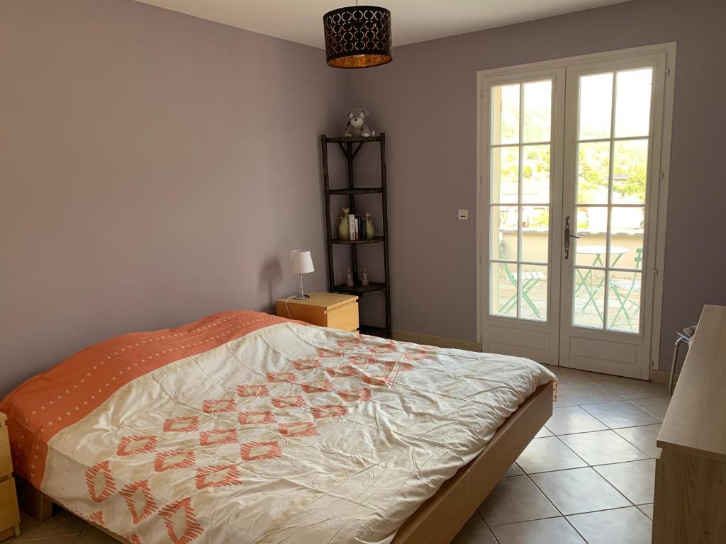 Schlafzimmer mit einem Bett und einer Glastür in der Unterkunft Le mas christine in Buis-les-Baronnies