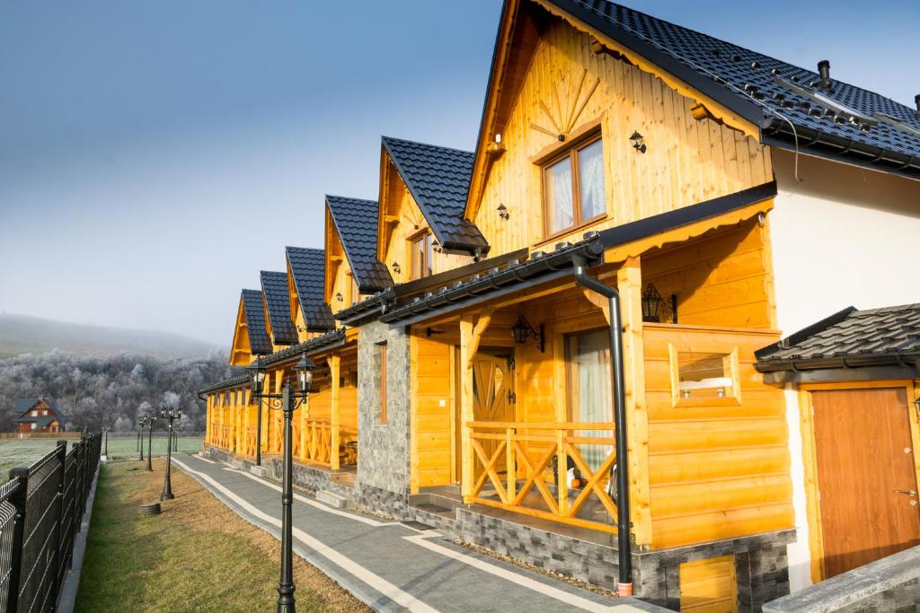 wiersz drewnianych budynków z płotem w obiekcie DW KINGA & DOMKI na Granicznej z jacuzzi w mieście Kacwin