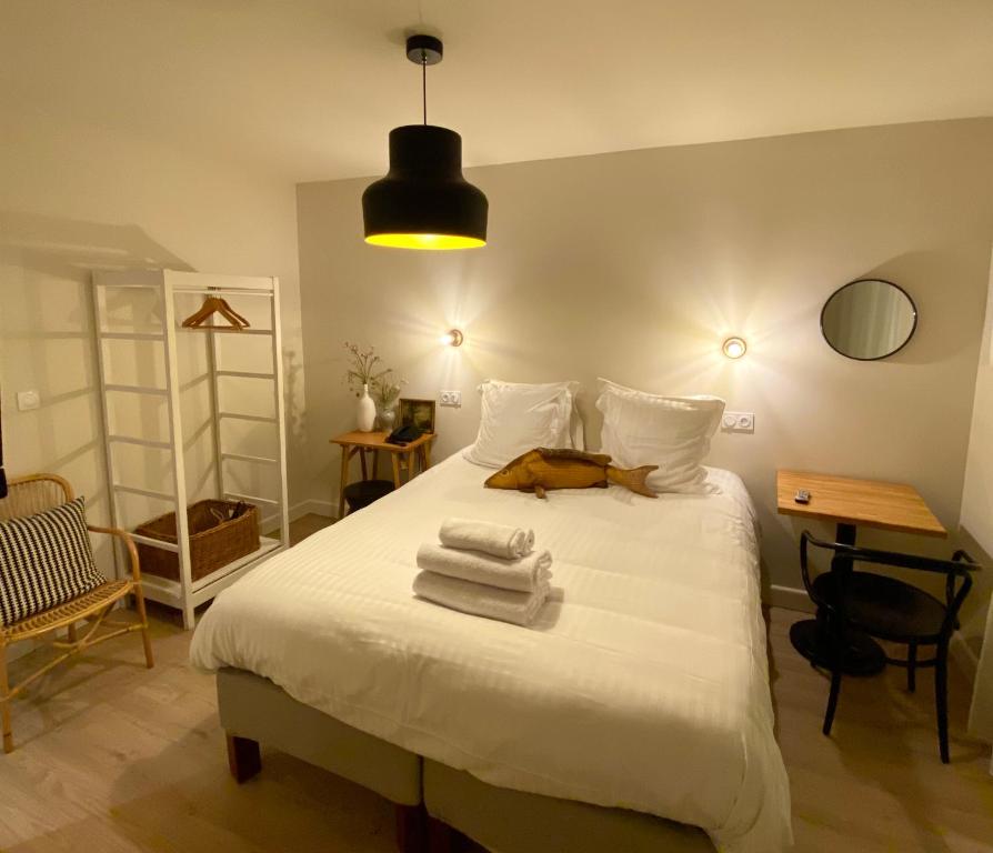 Un dormitorio con una cama blanca con toallas. en Hôtel Les Bains, en Saint-Valéry-en-Caux