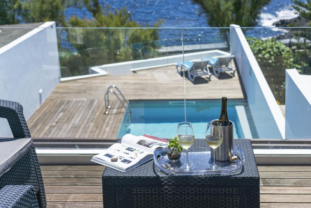 una mesa con una botella de vino y una copa en Thalassa Villas en Ponta Delgada