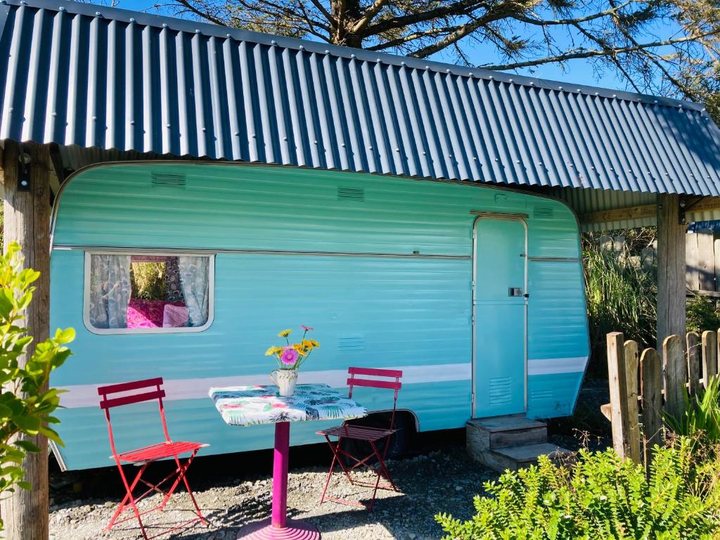 a table and chairs in front of a blue trailer at Retro Caravans at Valentia Island Escape in Valentia Island