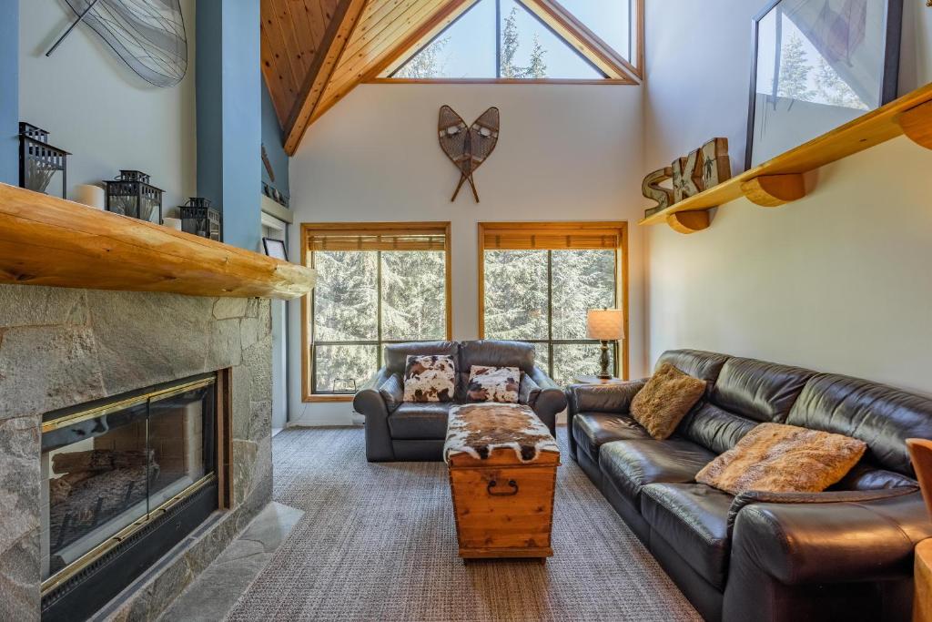 a living room with a leather couch and a fireplace at Powderhorn by Outpost Whistler in Whistler