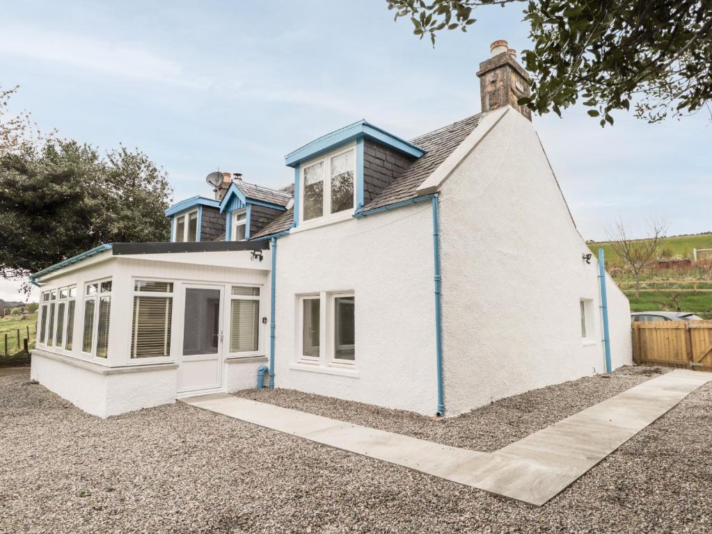 a white house with a blue roof at Balnaird Farmhouse in Strathpeffer