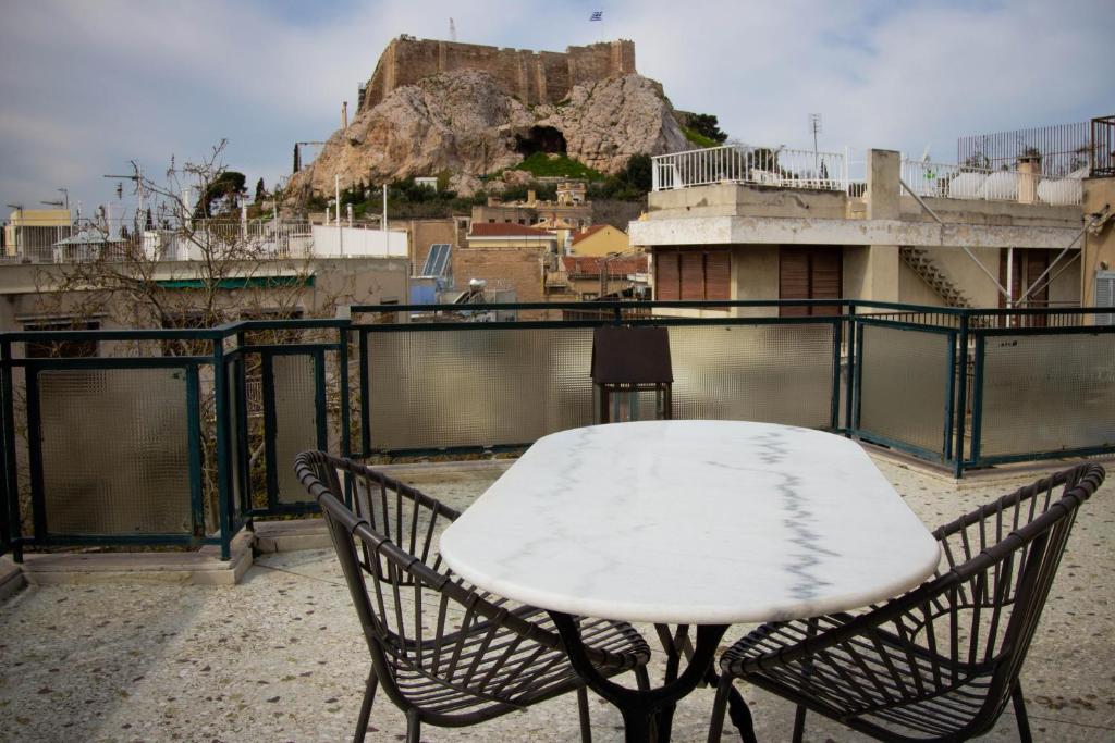 een witte tafel en 2 stoelen op een balkon bij Adam's Hotel in Athene