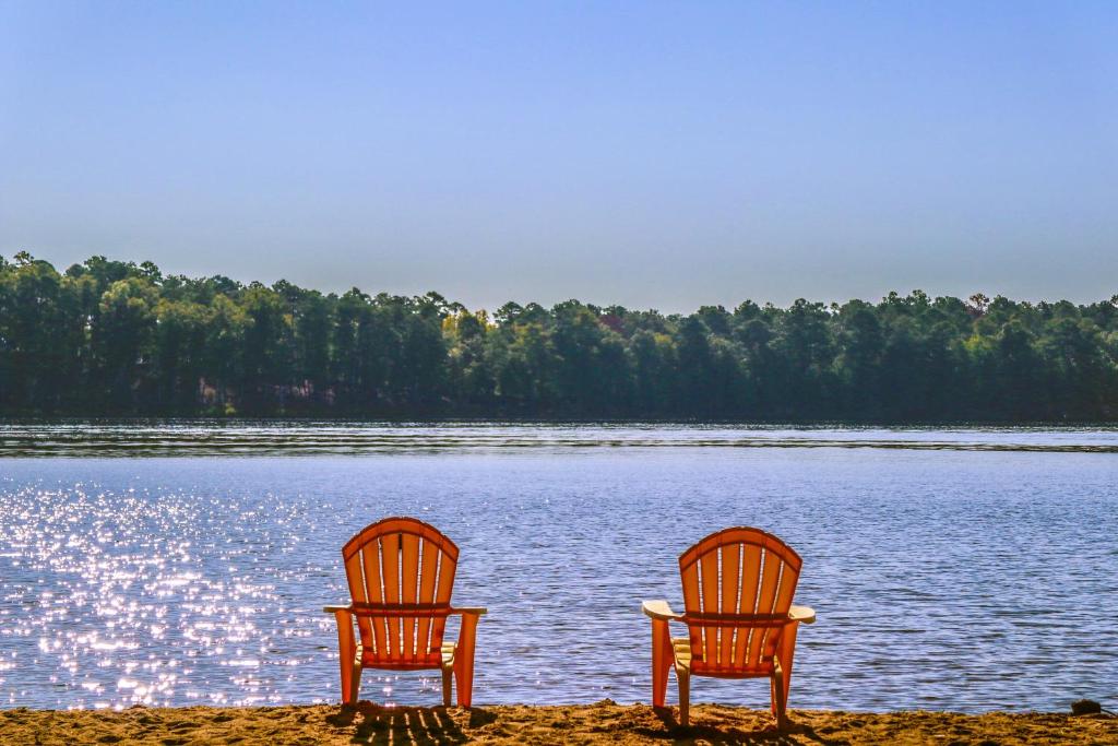 2 chaises assises sur la rive d'un lac dans l'établissement Park Place Great Waters Lakeside cottage, à Turnwold