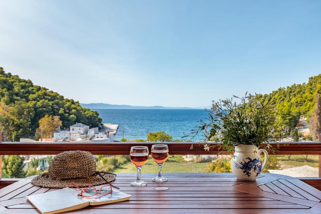 una mesa con 2 copas de vino en el balcón en Althea Accommodation, en Agnontas