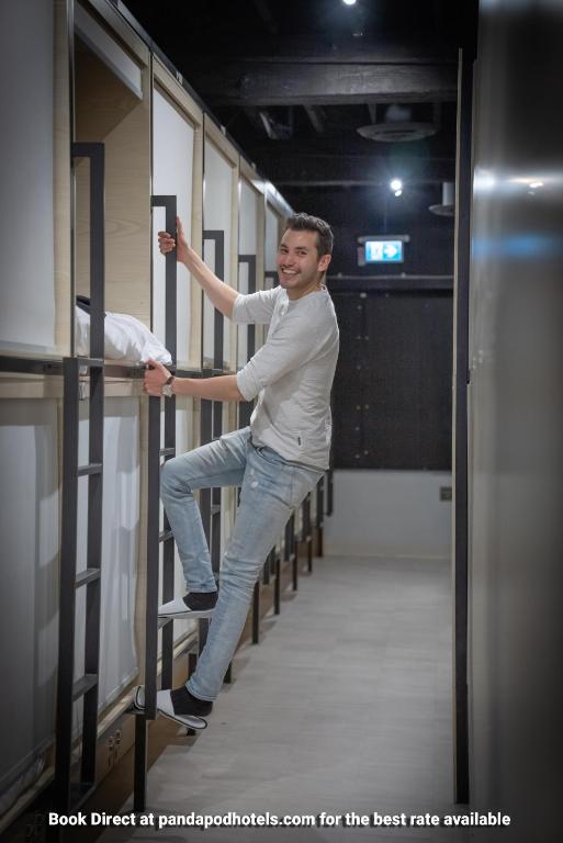 a man standing on a rail in a locker room at Panda Pod Hotel in Richmond