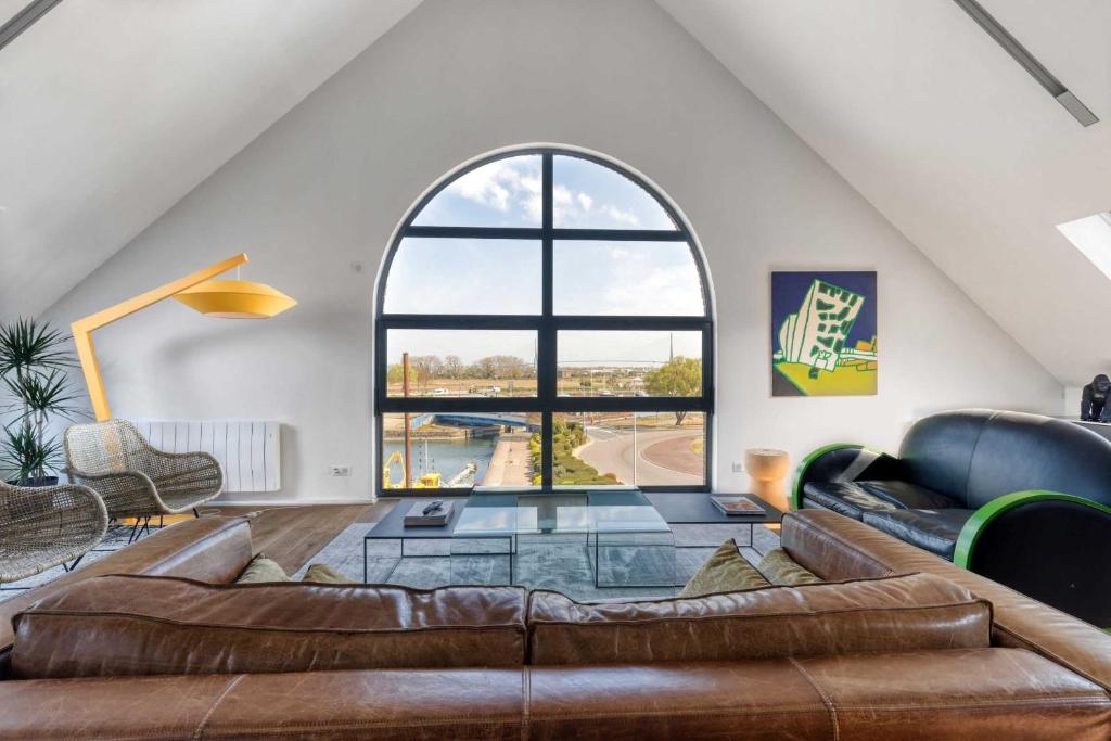 un salon avec un canapé et une grande fenêtre dans l'établissement Le Loft du Cosmopolitain, à Honfleur