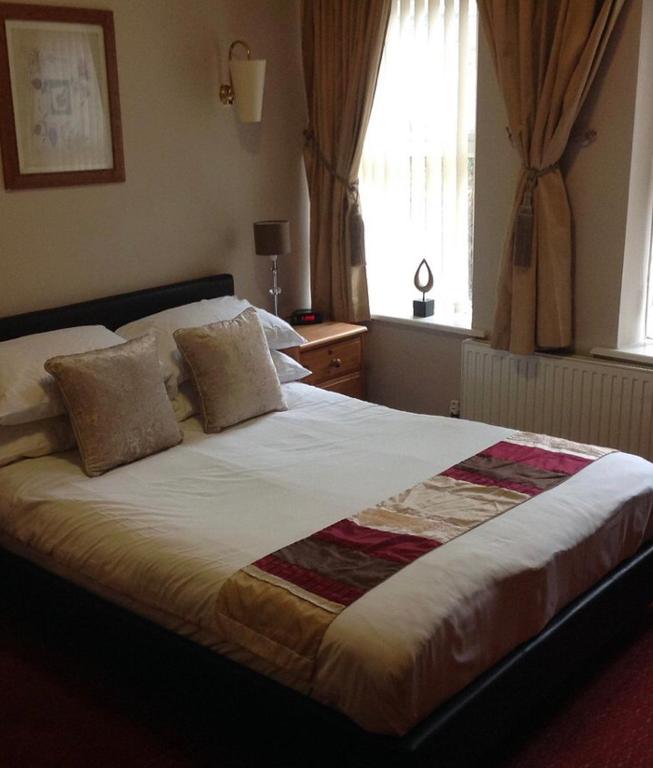 a large bed in a bedroom with a window at The Dillwyn arms in Swansea