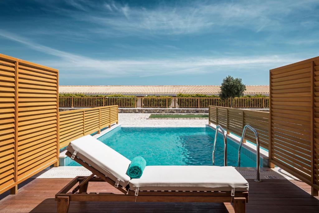 a swimming pool on a deck with a chaise lounge next to at Mitsis Selection Blue Domes in Kardamaina