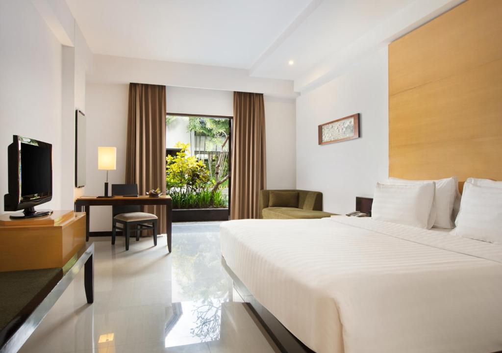 a hotel room with a bed and a television at Hotel Santika Premiere Malang in Malang