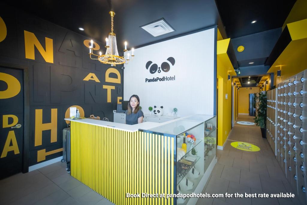 a woman is sitting at a counter in a store at Panda Pod Hotel in Richmond