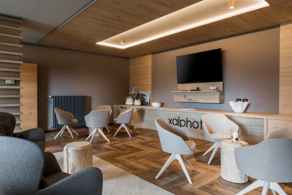 a waiting room with chairs and a flat screen tv at X Alp Hotel in Pozza di Fassa