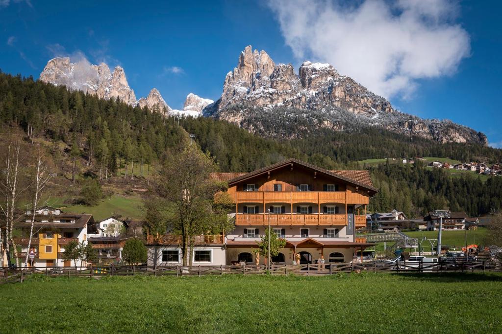a large building with a mountain range at X Alp Hotel in Pozza di Fassa