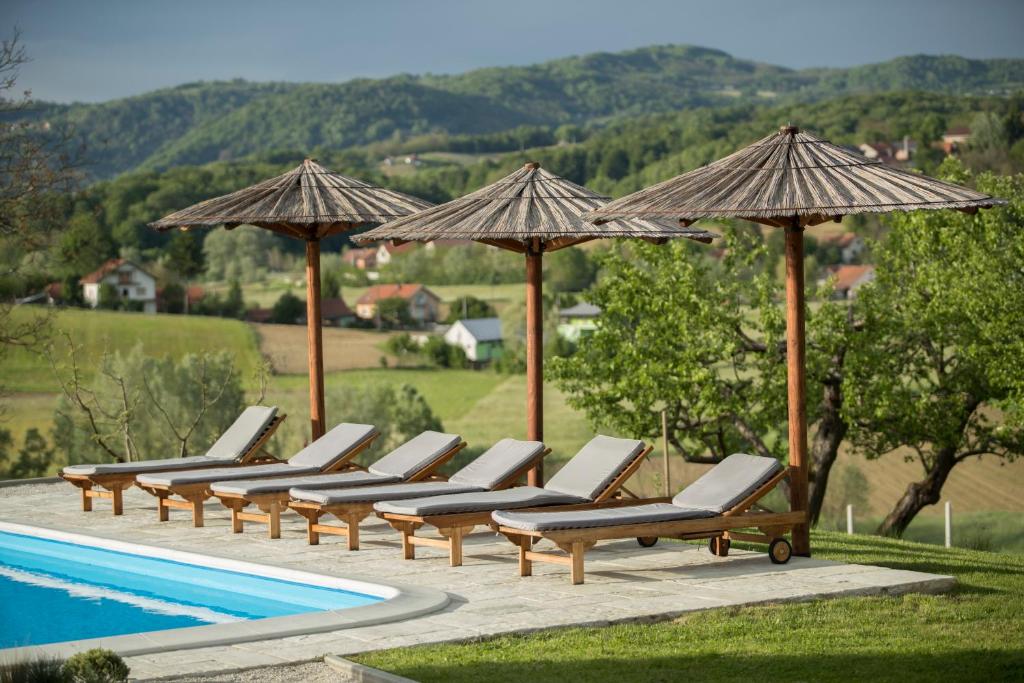 a row of lounge chairs and umbrellas next to a pool at Puhek breg in Krapina
