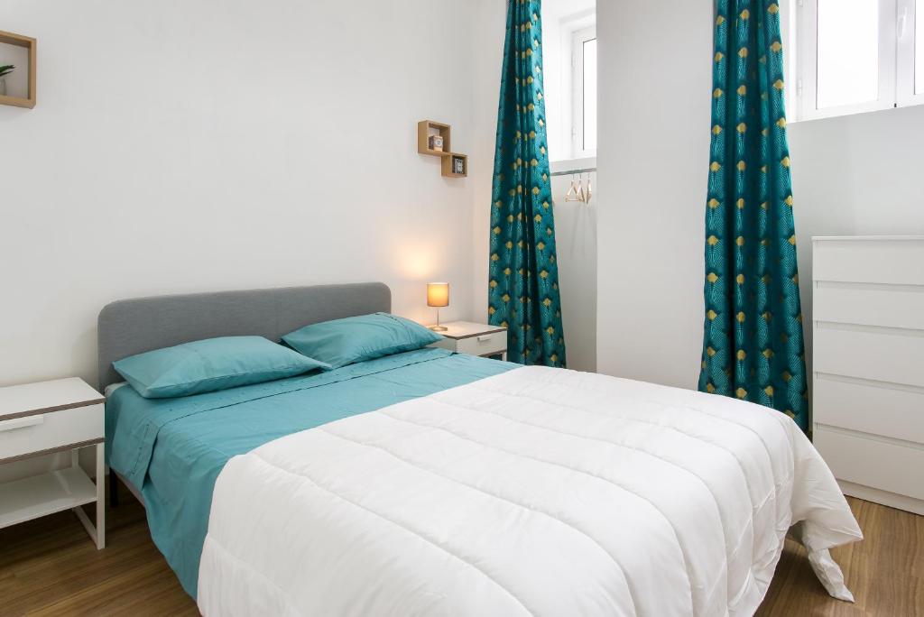Cozy Flat at Lisboa في لشبونة: غرفة نوم مع سرير أبيض كبير مع وسائد زرقاء