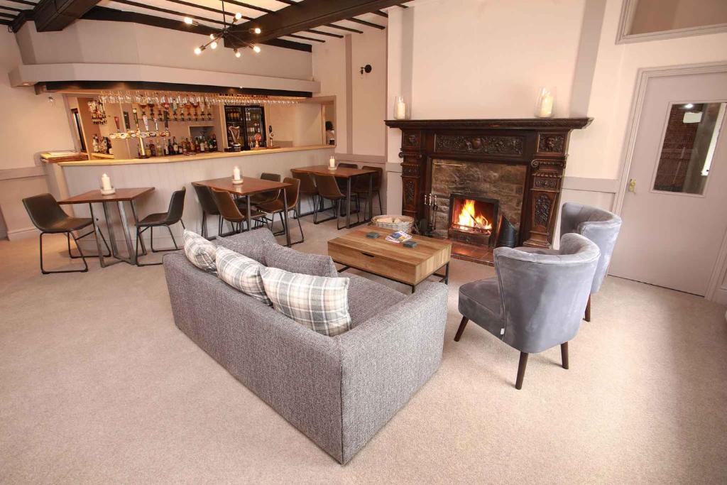 a living room with couches and a fireplace and a bar at Glyn Valley Hotel in Llansantffraid Glyn Ceiriog