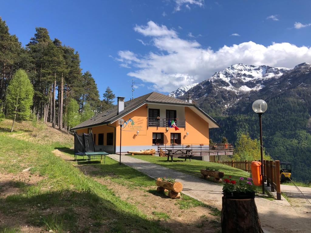 een klein geel huis met bergen op de achtergrond bij La Locanda Della Pineta in Bertonio