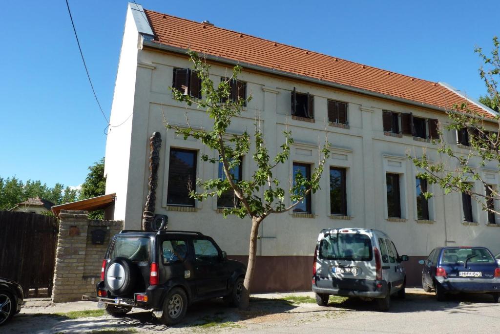 dwa samochody zaparkowane przed białym budynkiem w obiekcie Vadászkürt Vendégfogadó w mieście Alsónyék