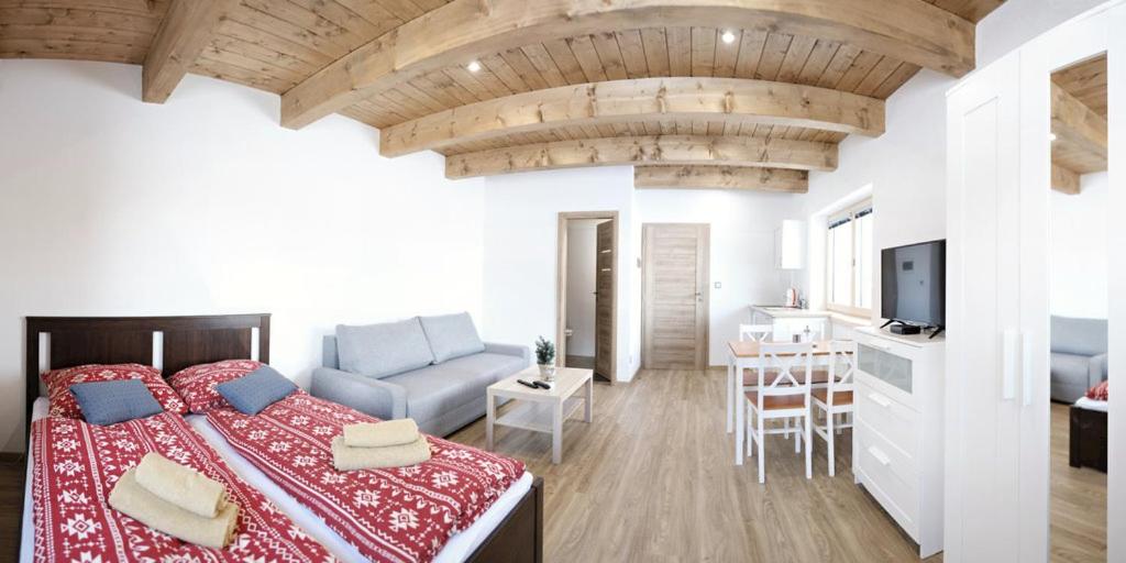 a bedroom with a bed and a living room at Apartmány pod horou in Liptovský Mikuláš