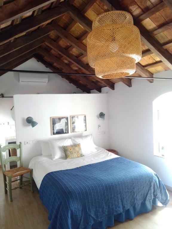 1 dormitorio con 1 cama con manta azul y lámpara de araña en La Puerta Azul, en Bornos