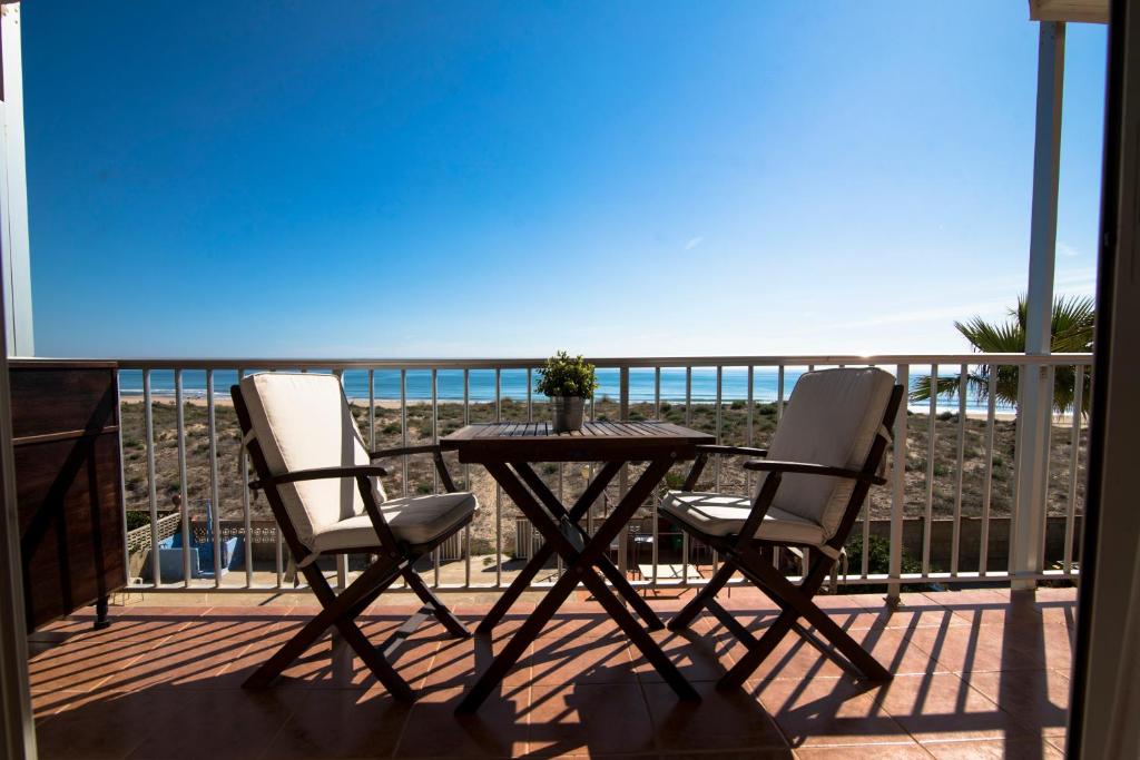 uma mesa e duas cadeiras numa varanda com o oceano em Beachfront at Perellonet em El Perellonet