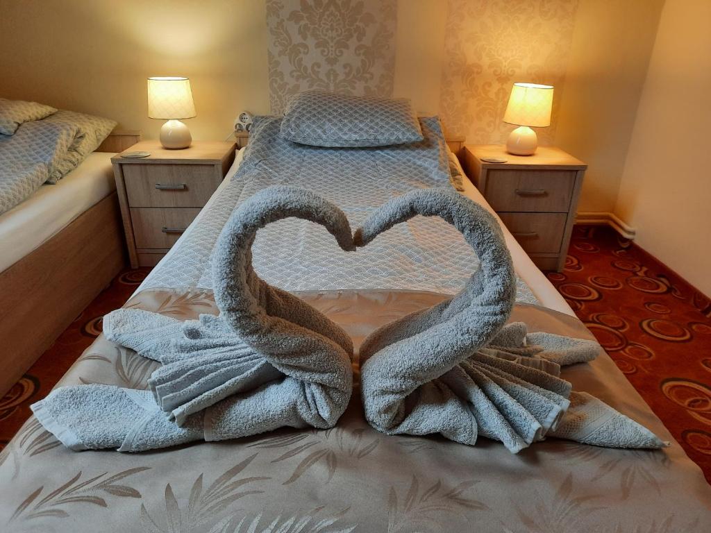 deux serviettes de cygne forment un cœur sur un lit dans l'établissement For You Apartman Gyula, à Gyula