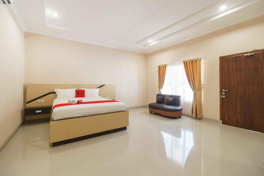 a bedroom with a bed and a chair in it at RedDoorz @ Hotel Copacobana Bengkulu in Bengkulu