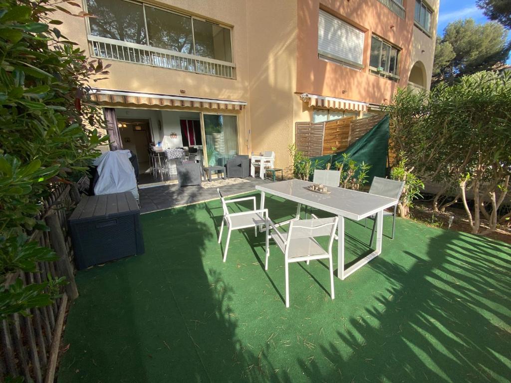 a patio with a white table and chairs in front of a building at Boost Your Immo Six Fours Les Plages Pinèdes Aryana 477 in Six-Fours-les-Plages