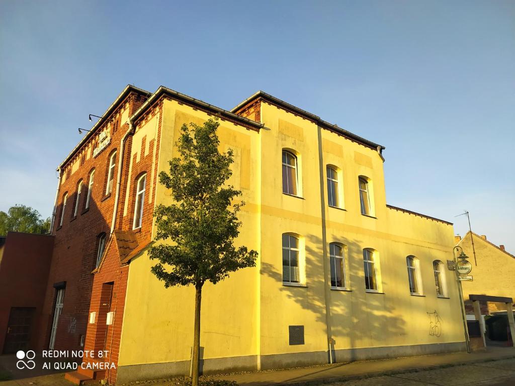 ヴォルガストにあるALTE MOLKEREI Wolgastの木の目の前の黄色い建物